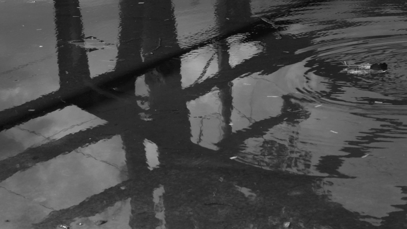 Au sol, reflet d'une structure dans une flaque d'eau. 