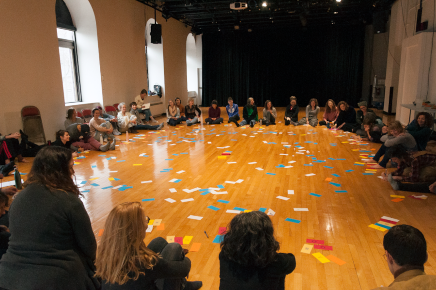 Dans une grande salle, les personnes participantes sont en cercle et on voit beaucoup de Post-it au centre.