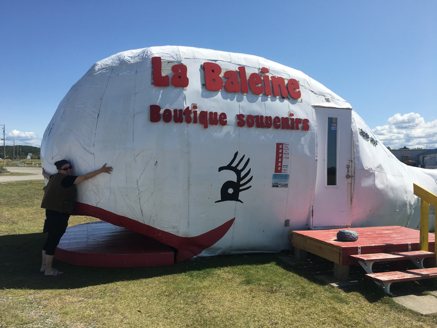 L'artiste fait un câlin à une boutique souvenirs en forme de baleine souriante.
