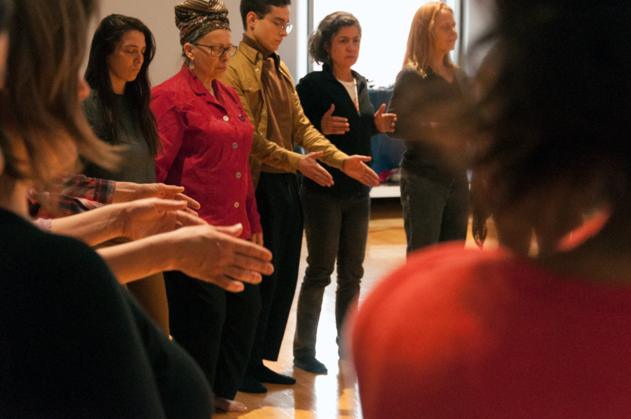 Des personnes, placées en cercle, semblent méditer debout.