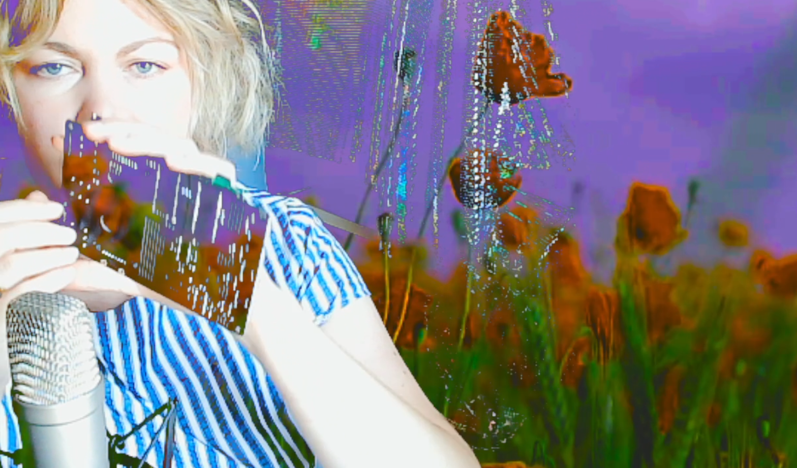 Captation vidéo d'Erin Gee tenant une carte-mère informatique devant sa bouche et ayant un fond fleuri