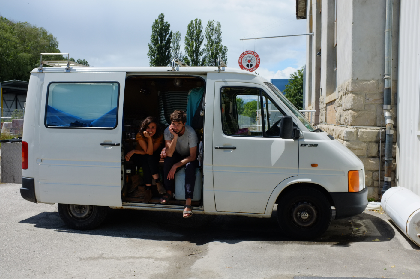 Deux personnes souriantes, le visage dans la main, dans une mini-fourgonnette dont la porte latérale est ouverte.