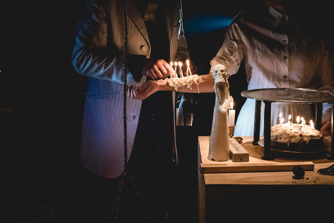 Deux personnes en train d'allumer des bougies sur un gâteau et sur un bras, avec un éclairage tamisé contribuant à une atmosphère intime