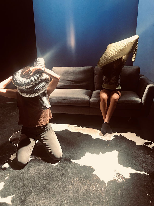 Deux personnes sur un sofa, l'un avec un tuyau de sécheuse sur la tête et l'autre un coussin